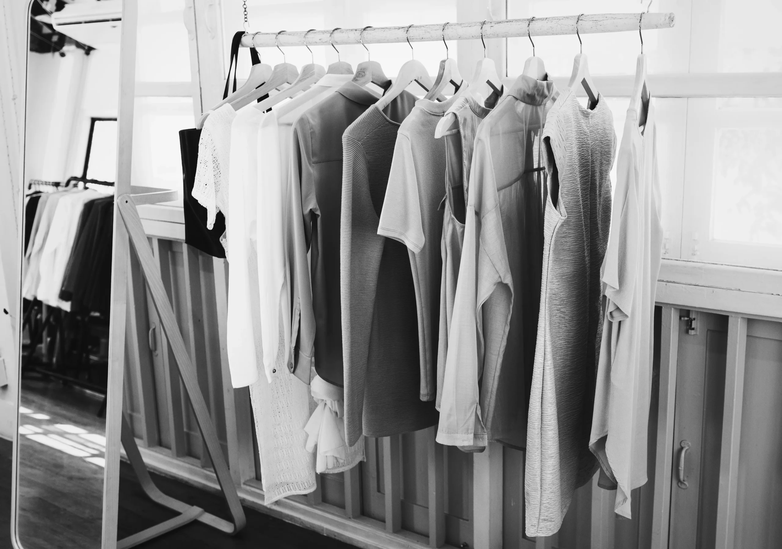 Fotografía en blanco y negro de prendas colgadas en un perchero.