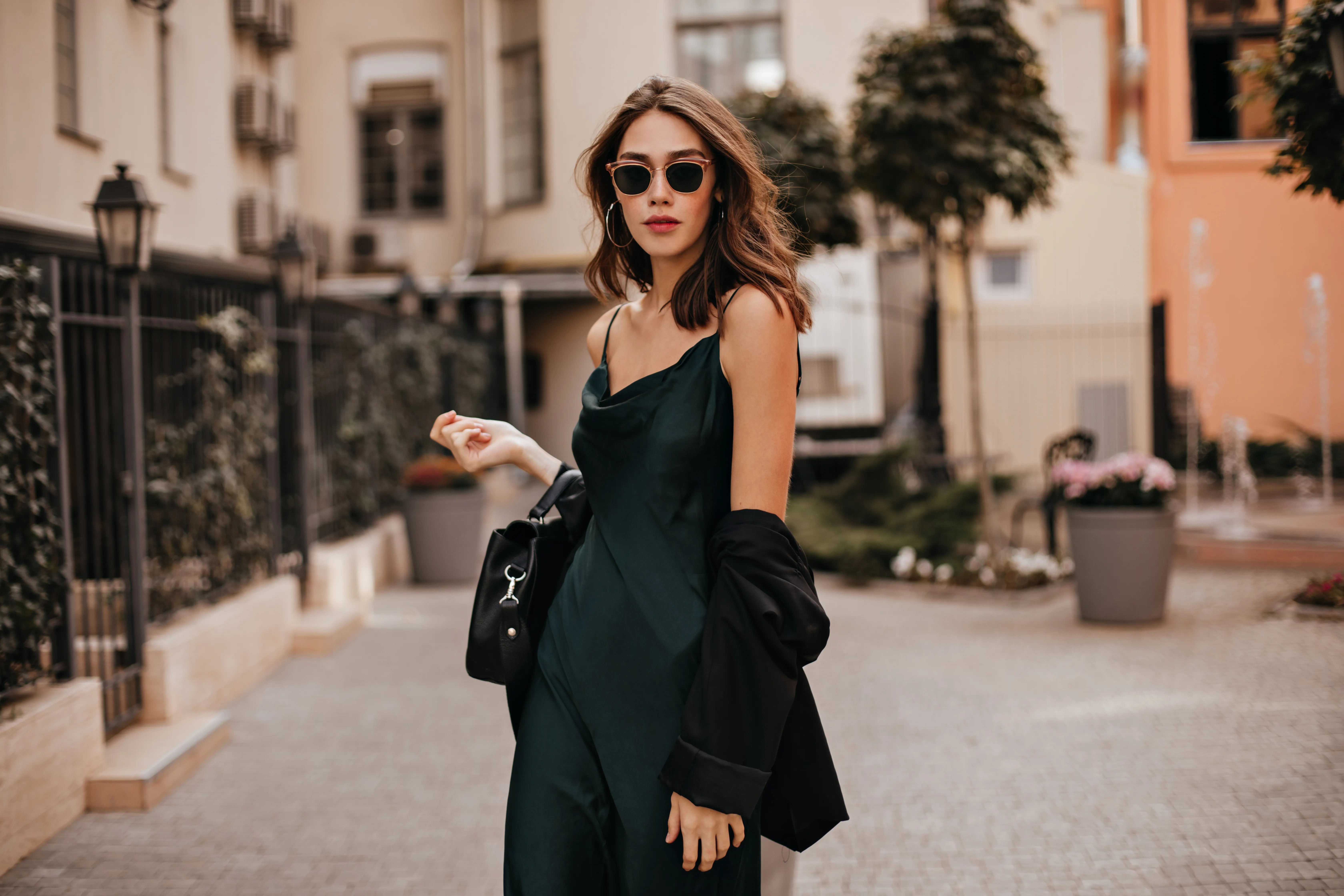 Mujer posando en la calle con un vestido verde oscuro y gafas de sol.